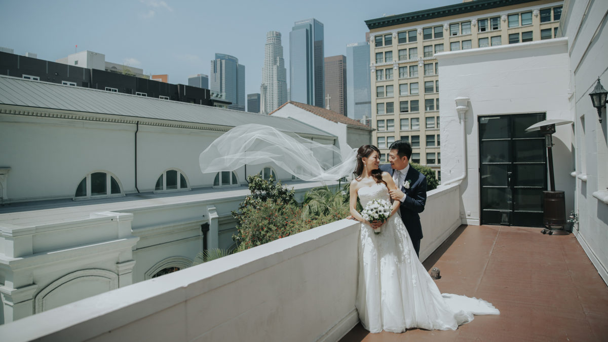 bride and groom on top floor patio with brides veil floating in the wind
