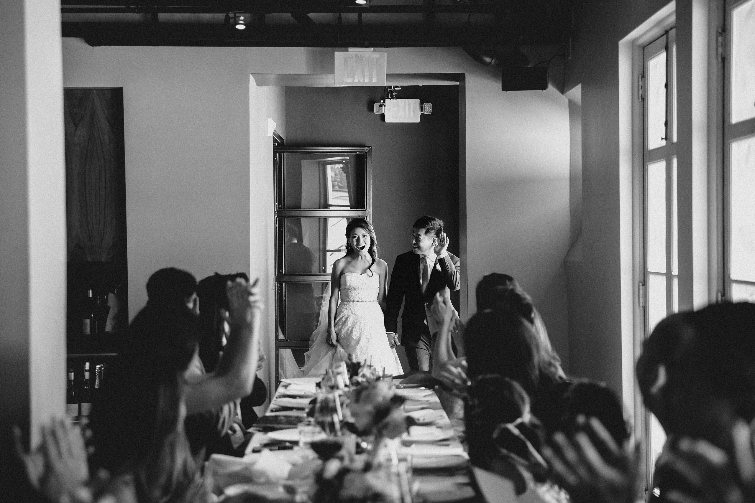 black and white photo of bride and groom entering their reception