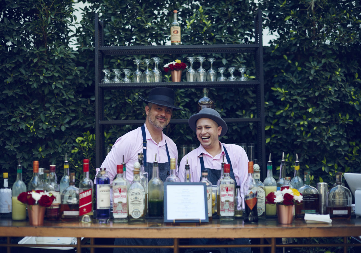 two bartenders in top hats behind outdoor bar