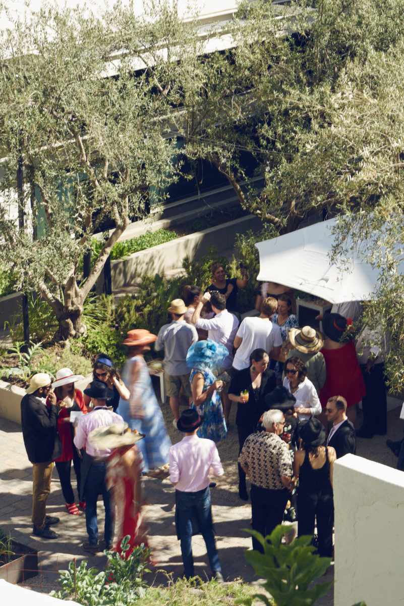 outdoor garden party with guests wearing hats and mingling