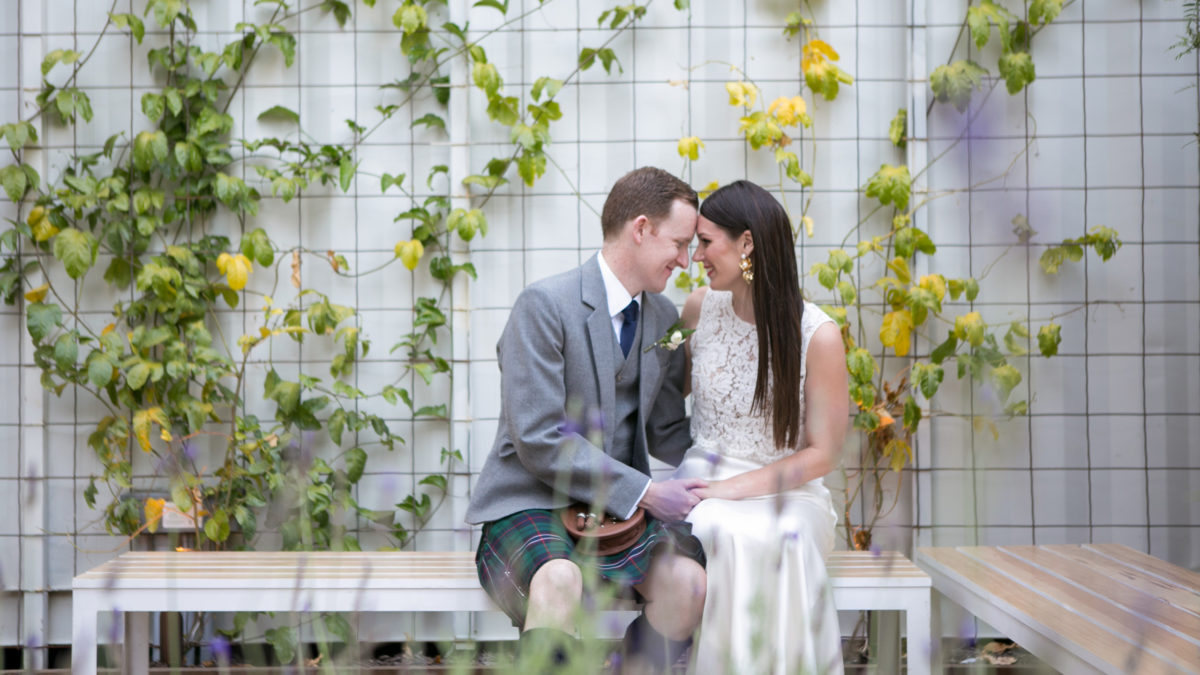 bride and groom seated on benches in garden