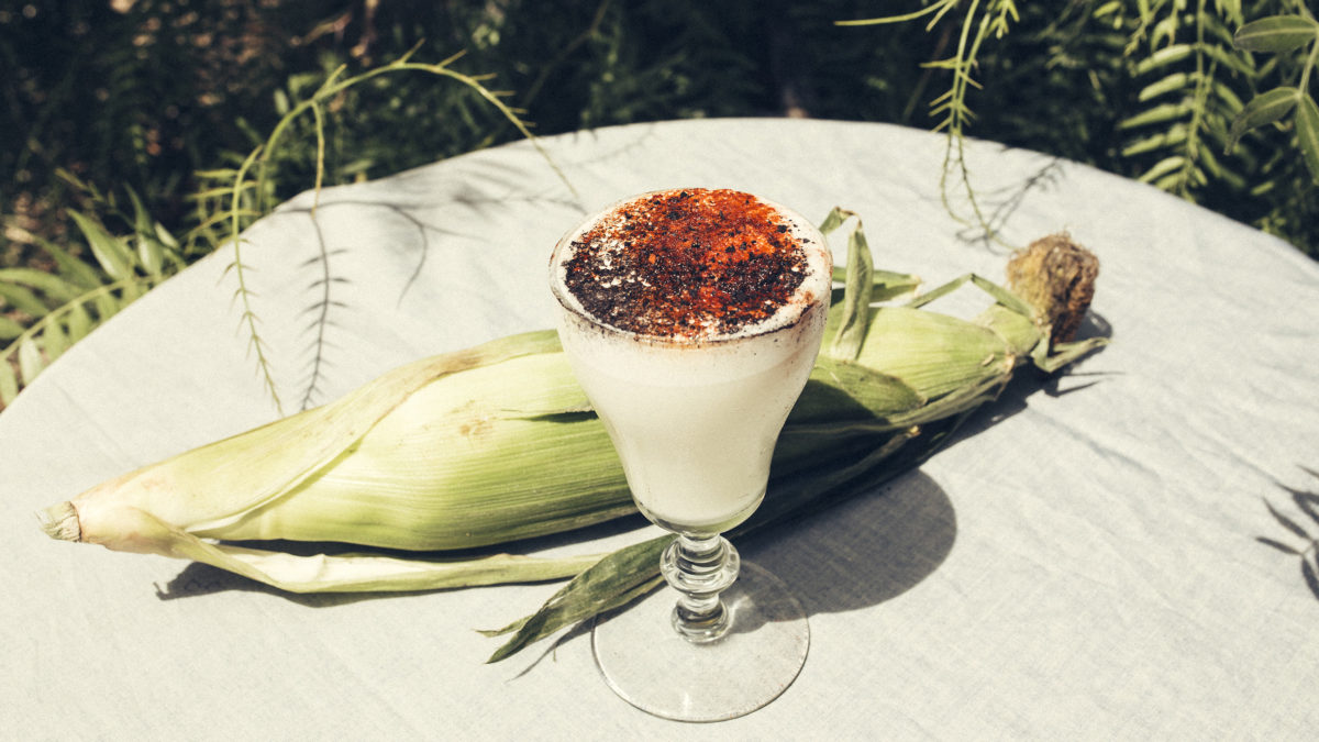 garden table set with spiced cocktail and a husk of corn