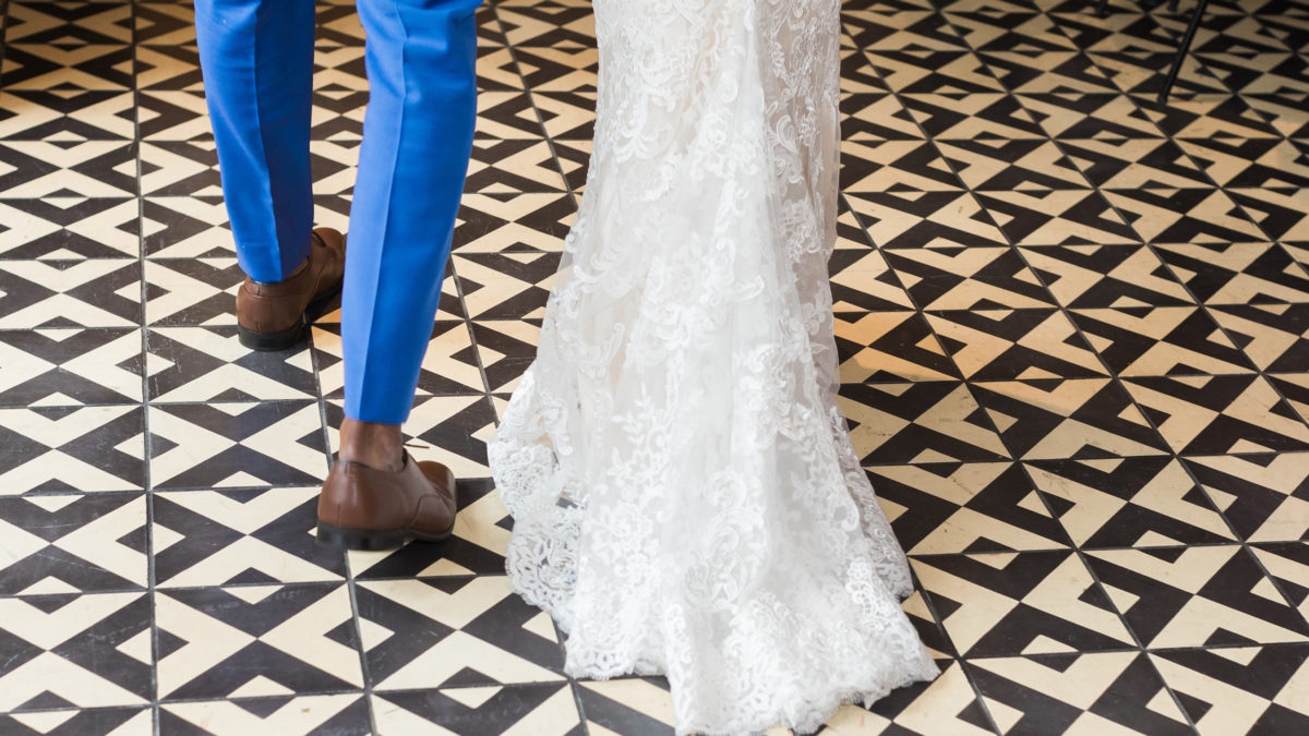 bride and grooms lower legs walking across back and white tiled floor