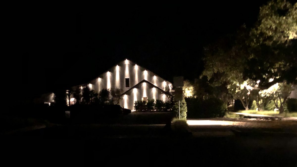 nighttime building with lights on surrounded by trees