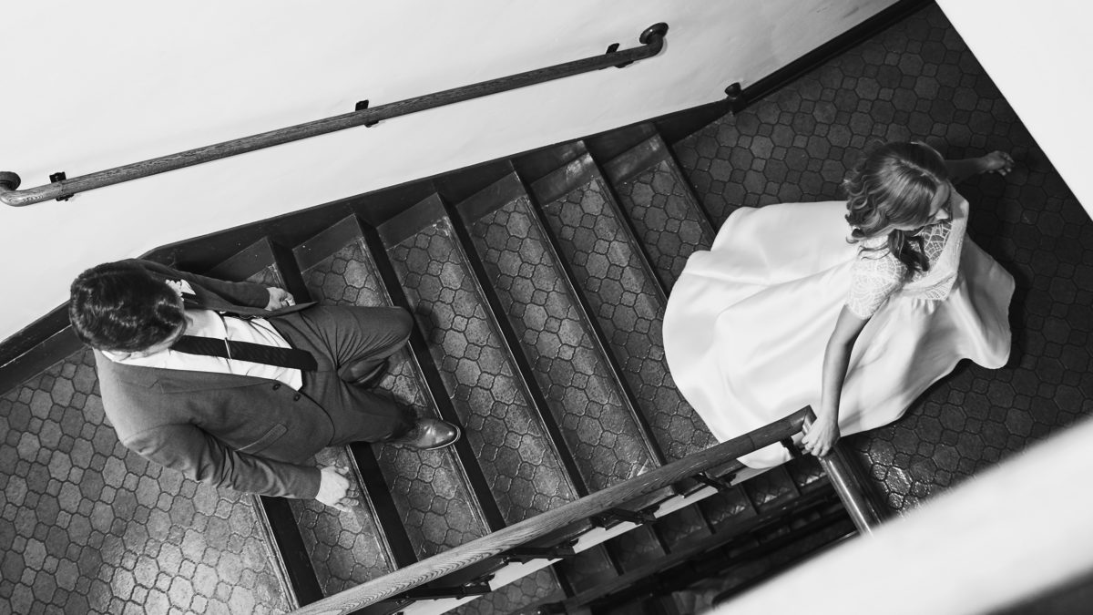 black and white shot of bride and groom walking down stairs
