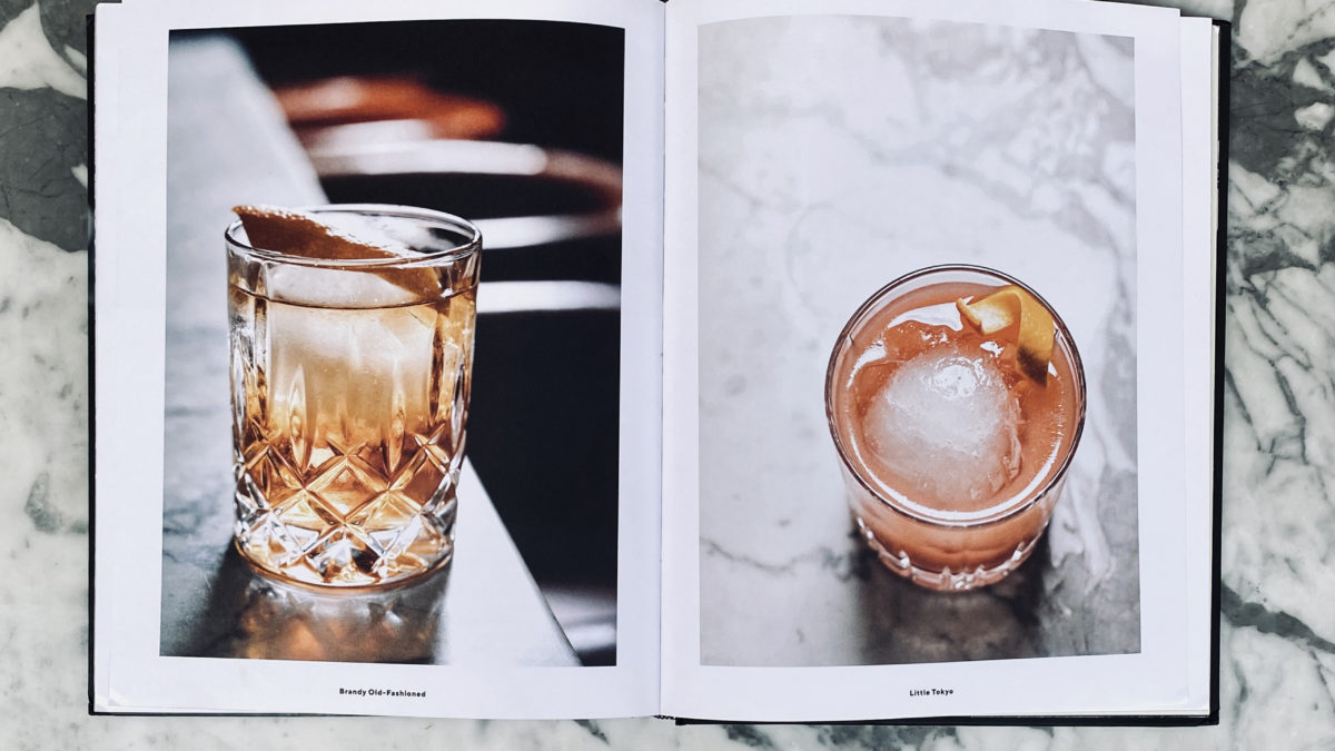 Cocktail book opened on bar to show two cocktails