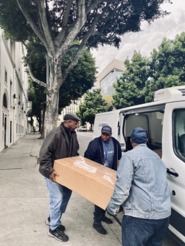 three men loading a heavy box into a van