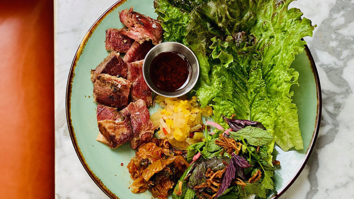 lamb belly with lettuce on a marble bar with orange stool