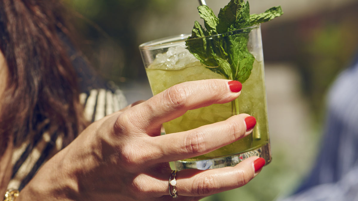 woman with red nail polish holding mint julep