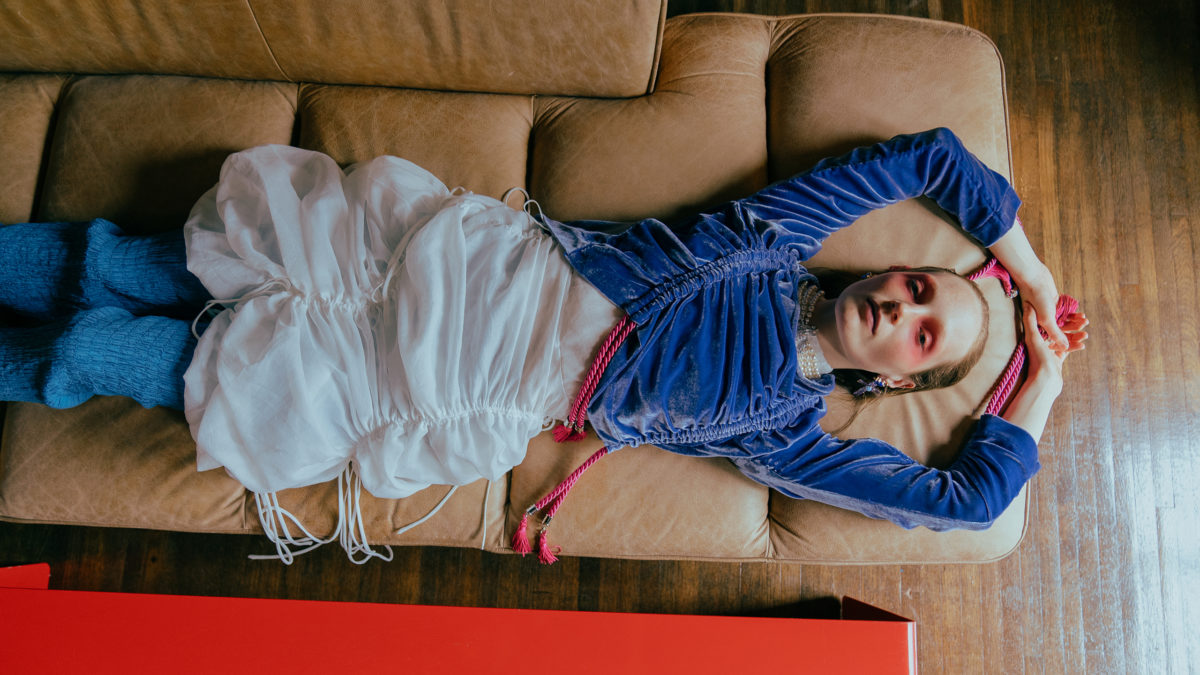 model in blue shirt lying on couch