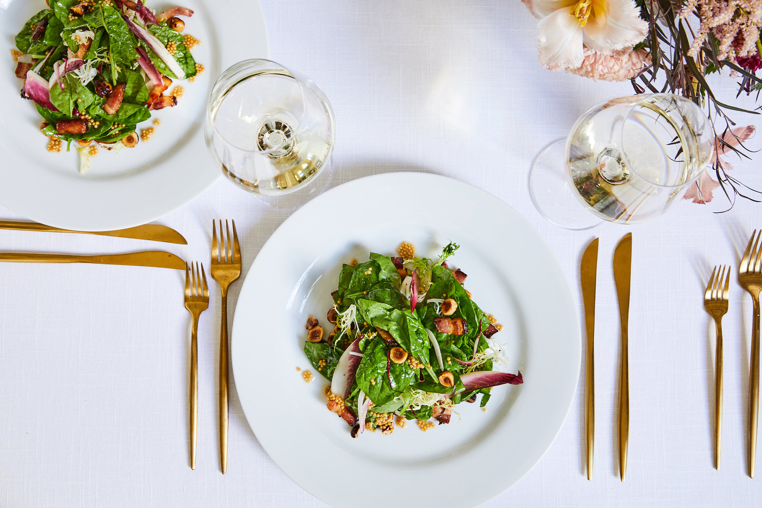 salads on a white table cloth with gold serving ware 