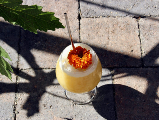 yellow cocktail with orange flower on the ground