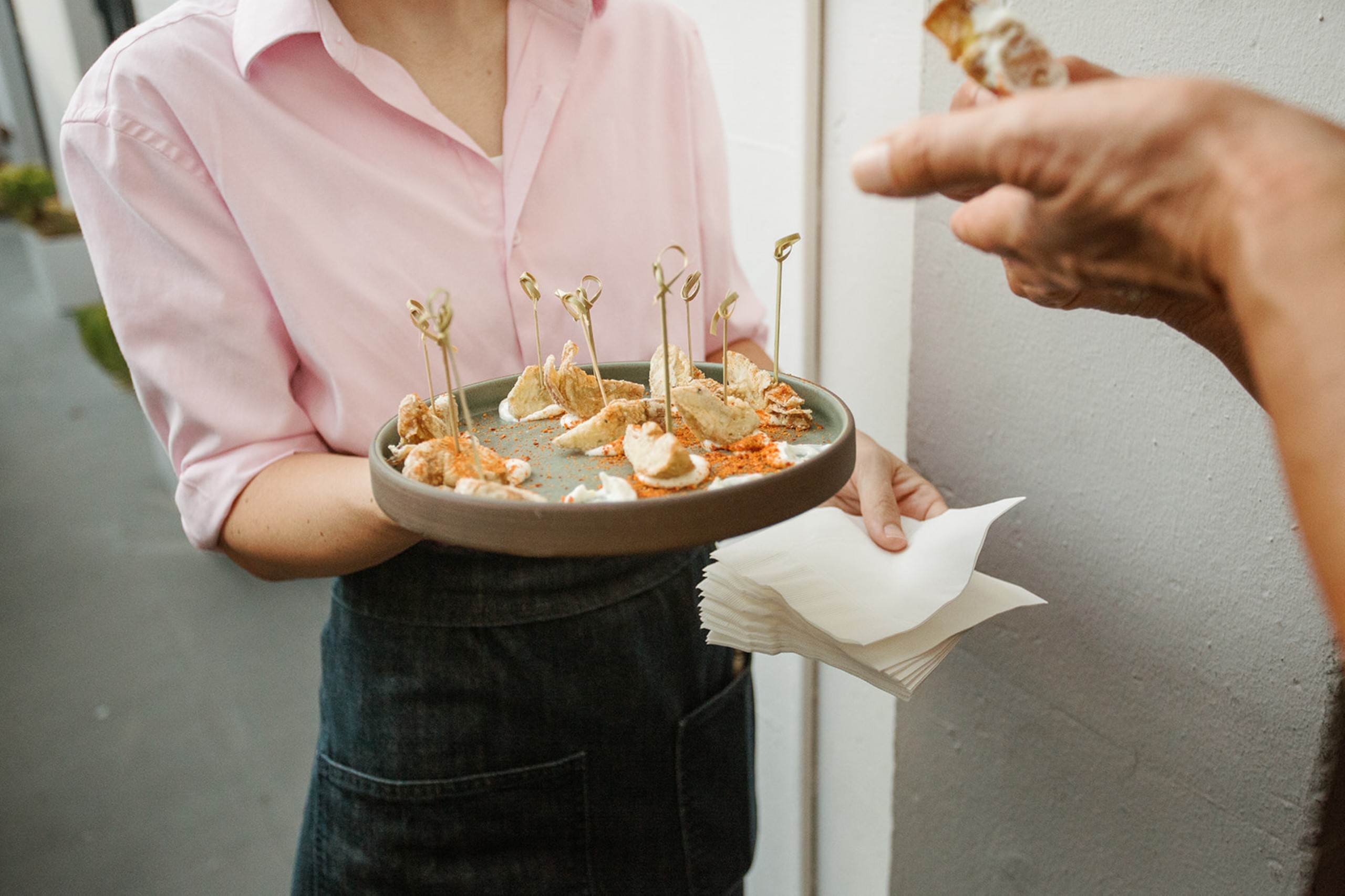 fried artichokes being passed by a server in a pink shirt