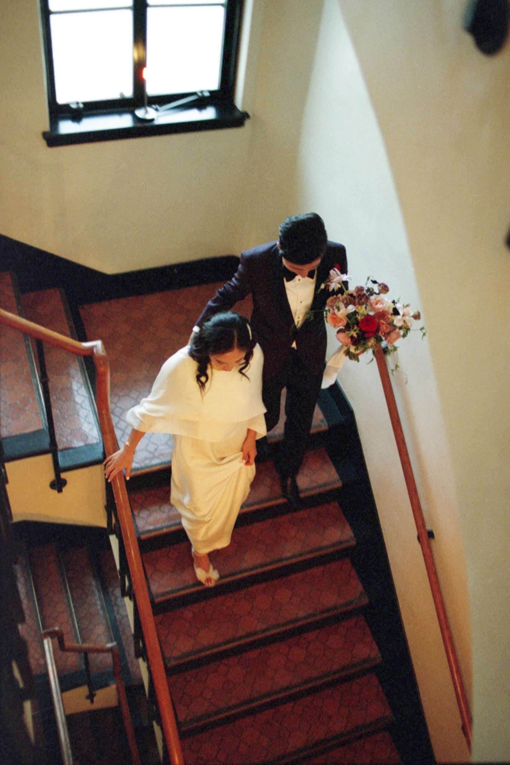 couple walking downstairs with flowers