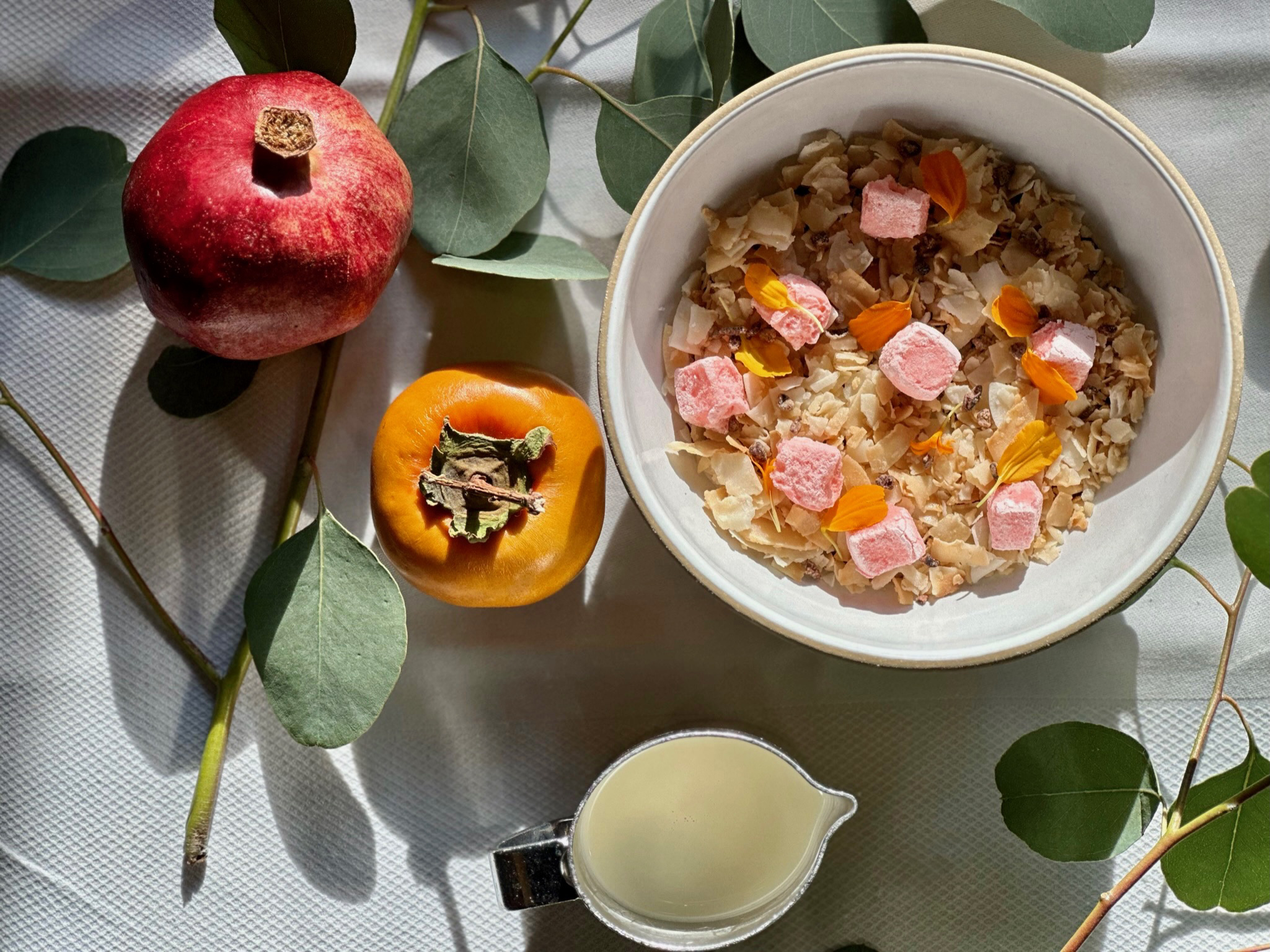food dessert cereal pomegranate and persimmon surrounded by leaves on white