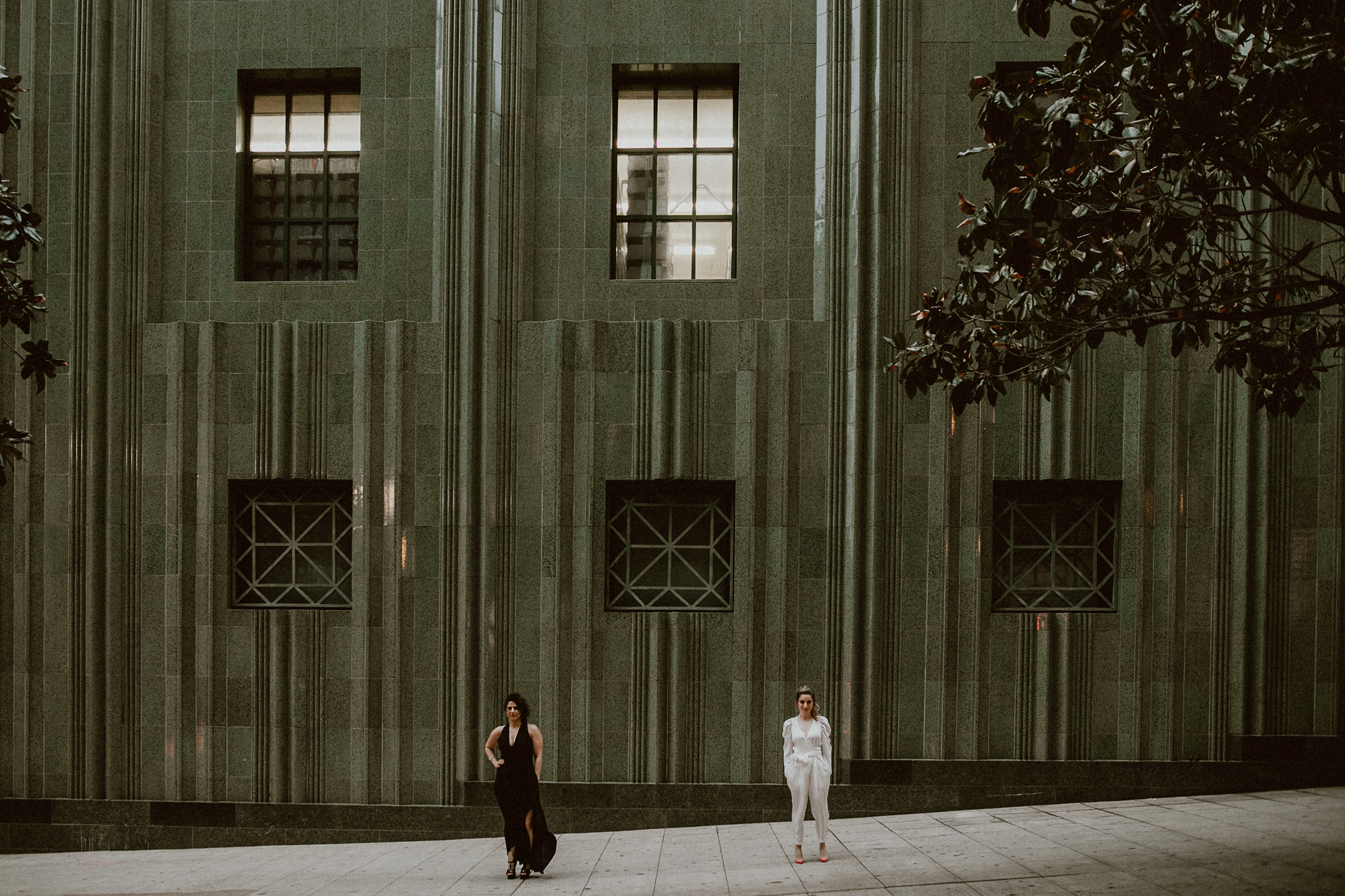 two people standing in DTLA in front of green building 