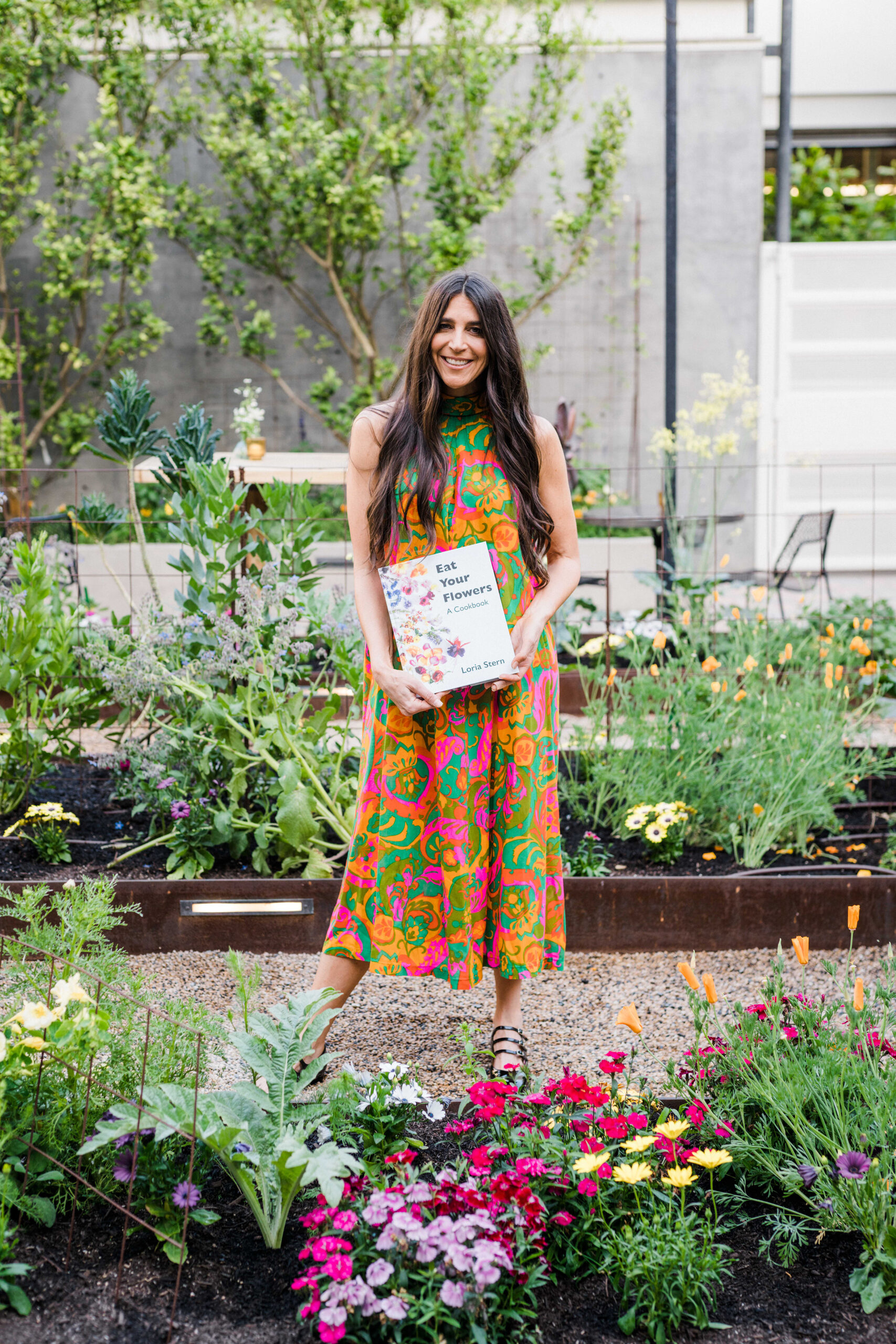 brunette woman in garden holding a cookbook